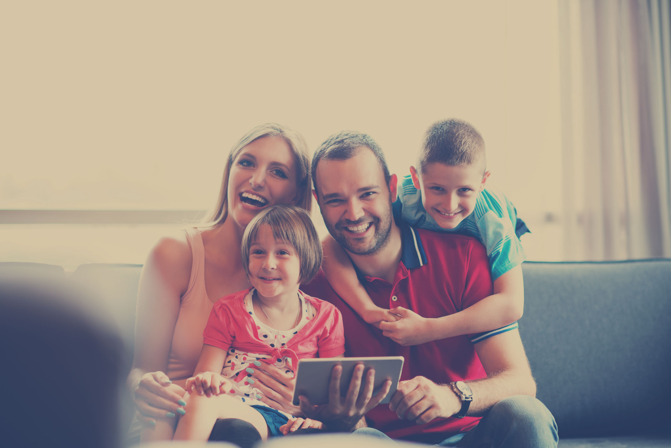 Happy family on sofa at home with tablet computer